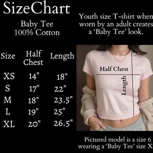 May include: Size chart for a baby tee, made of 100% cotton. The chart shows the size, half chest measurement in inches, and length in inches. The chart includes sizes XS, S, M, L, and XL. A model is wearing a size XS baby tee.