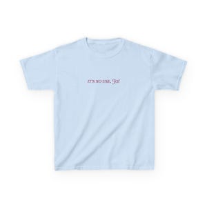 May include: A light blue t-shirt with the text "IT'S NO USE, GO!" printed in pink.