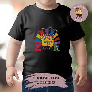 May include: Black t-shirt with a colorful graphic featuring the text "Happy Birthday," "It's Wiggle Time!" and the name "Avery." The number "2" is prominently displayed. A small graphic of a green dinosaur is also present.