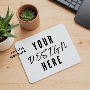 Puede incluir: Alfombrilla de ratón blanca con el texto "YOUR DESIGN HERE" en letras negras. La alfombrilla de ratón está sobre una superficie de madera clara con una pequeña planta en maceta y un teclado.