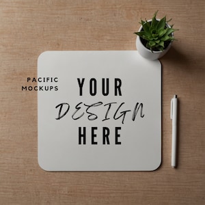 Puede incluir: Maqueta cuadrada blanca con el texto "YOUR DESIGN HERE" y las palabras "PACIFIC MOCKUPS" en la esquina superior izquierda. Un bolígrafo blanco y una planta suculenta en maceta están sobre una superficie de madera.