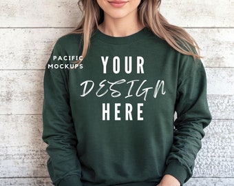 May include: A dark green sweatshirt with long sleeves and a crew neck. The text "YOUR DESIGN HERE" is printed in white on the front of the sweatshirt.