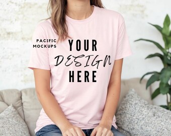 Puede incluir: Camiseta rosa claro con el texto negro "YOUR DESIGN HERE". La camiseta es de cuello redondo. Las palabras "PACIFIC MOCKUPS" están en la esquina superior izquierda.