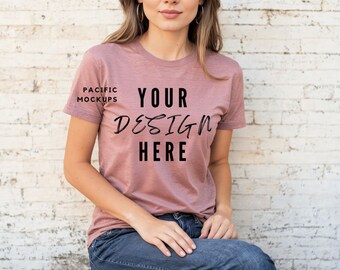 May include: A mauve t-shirt with short sleeves and a crew neck. The shirt has the text "YOUR DESIGN HERE" printed on the front. The text is in black and has a handwritten style font.