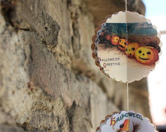 May include: A Halloween garland with three paper circles. The first circle features a vintage illustration of a witch and a black cat. The second circle features a vintage illustration of pumpkins with the text "Hallowe'en Greeting". The third circle features a vintage illustration of a child dressed as a witch with a black cat.