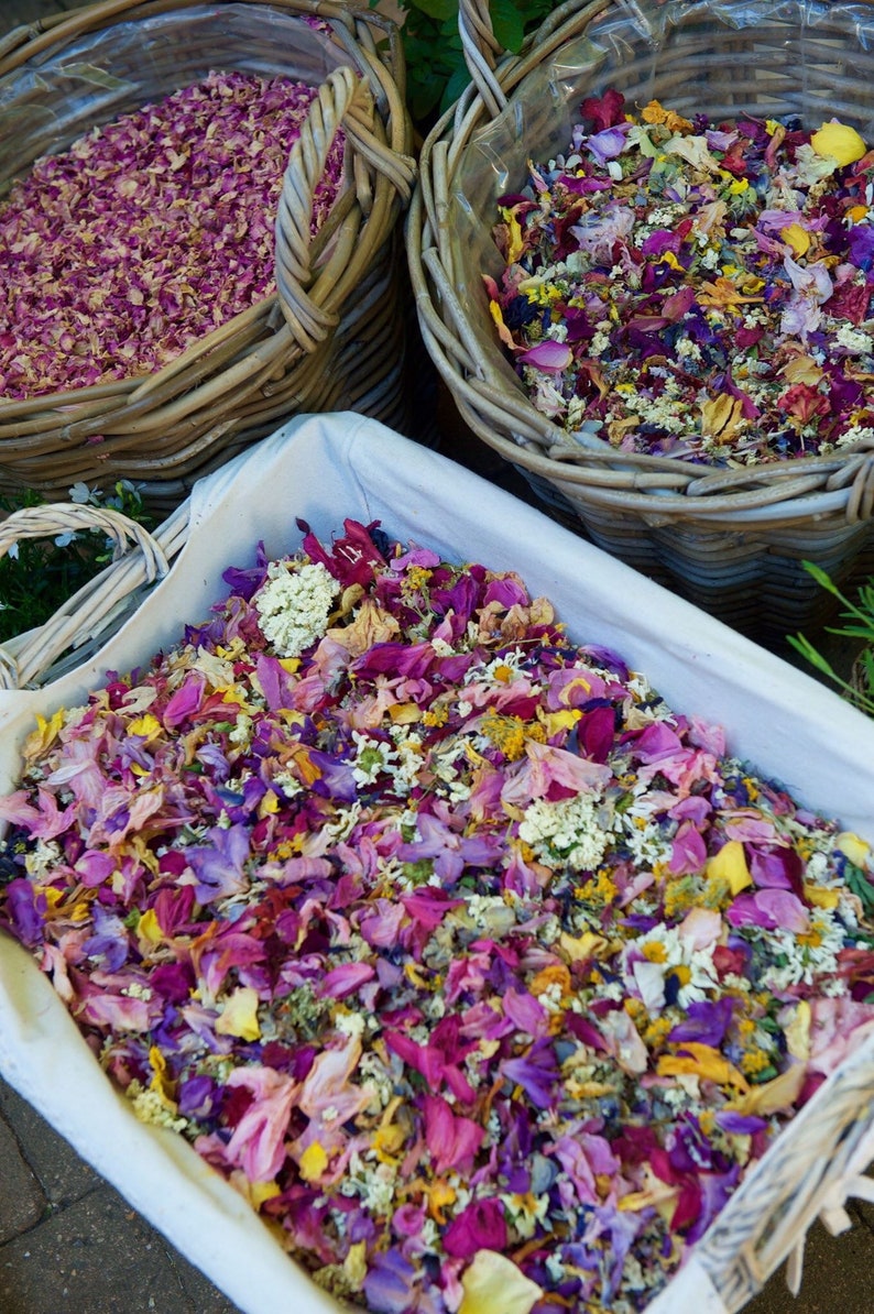 Pu&ograve; includere: Un cesto di vimini bianco pieno di un mix di petali di fiori secchi in tonalit&agrave; di rosa, viola, giallo e bianco.