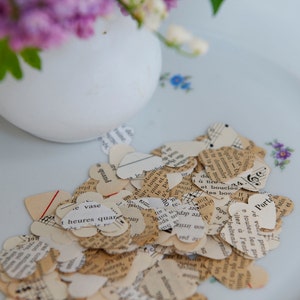 Puede incluir: Un plato blanco con una dispersi&oacute;n de peque&ntilde;os corazones de papel cortados de viejas p&aacute;ginas de libros. Los corazones son de varios tonos de crema y beige, algunos mostrando notas musicales y texto.