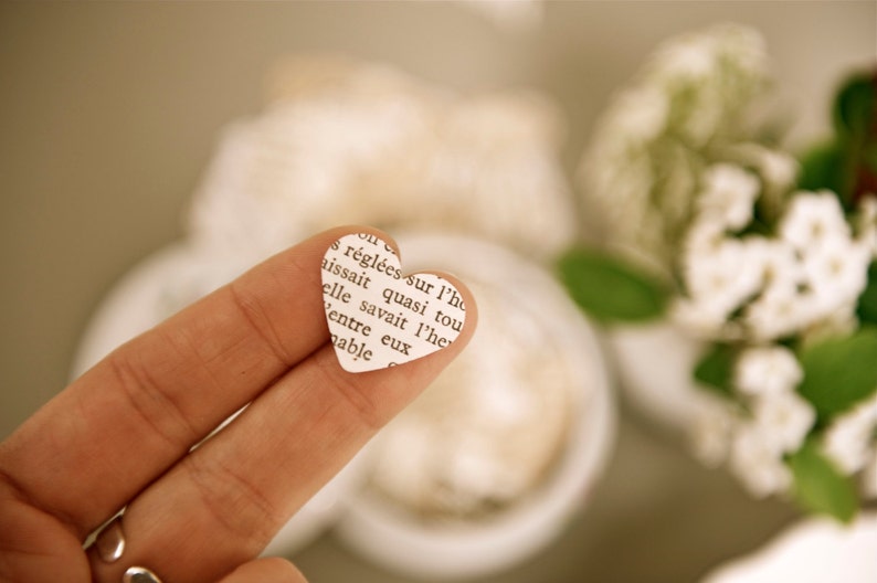 Puede incluir: Un dedo sosteniendo un peque&ntilde;o trozo de papel en forma de coraz&oacute;n con texto impreso. El texto dice "r&eacute;gl&eacute;es sur l'ho issait quasi tou elle savait l'he entre eux nable"