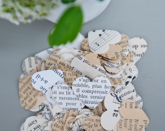 May include: A pile of heart-shaped confetti made from recycled sheet music. The confetti is in shades of cream, white, and brown. The confetti features musical notes and text in French.