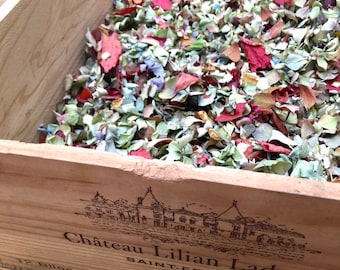 May include: A wooden box filled with dried flower petals in shades of pink, purple, and green. The box is labeled "Château Lilian Ladouys Saint-Estèphe".