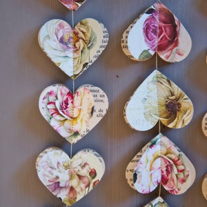 Puede incluir: Una guirnalda de corazones de papel con motivos florales, cada coraz&oacute;n est&aacute; conectado por una cuerda. Los corazones est&aacute;n hechos de viejas p&aacute;ginas de libros con una est&eacute;tica vintage.