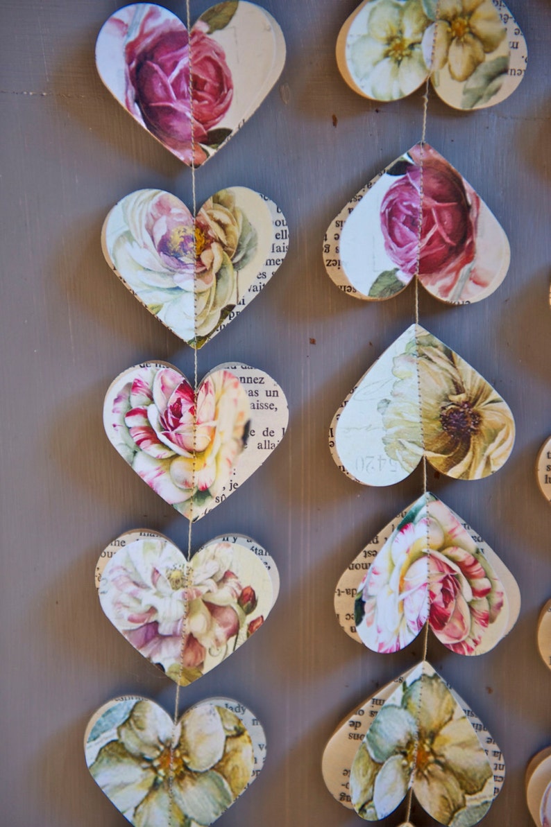Puede incluir: Una guirnalda de corazones de papel con motivos florales, cada coraz&oacute;n est&aacute; conectado por una cuerda. Los corazones est&aacute;n hechos de viejas p&aacute;ginas de libros con una est&eacute;tica vintage.