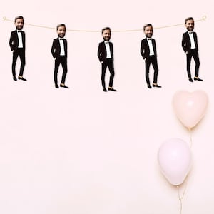 May include: A string of five black and white images of men in tuxedo suits hanging from a string with two pink heart-shaped balloons below.