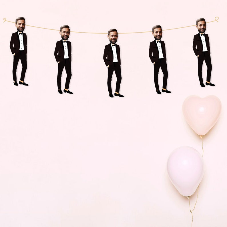 May include: A string of five black and white images of men in tuxedo suits hanging from a string with two pink heart-shaped balloons below.