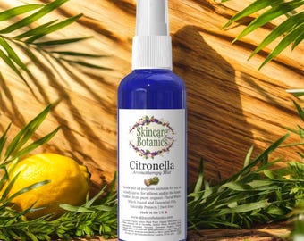 Può includere: Una bottiglia di nebbia aromaterapica blu con un'etichetta bianca con il testo "Citronella Aromatherapy Mist" e "Skincare Botanics". La bottiglia è posta su uno sfondo di legno con fogliame verde e un limone giallo.