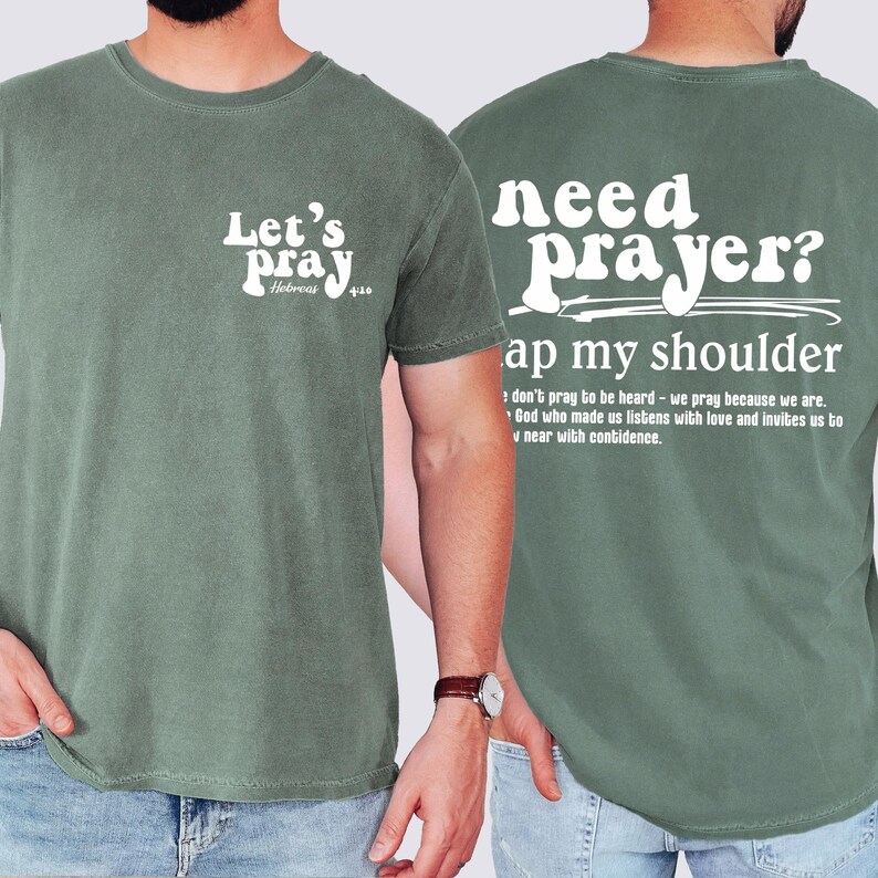 May include: Sage green t-shirt with white text. The front reads "Let's pray" with "Hebrews 4:16" below. The back says "need prayer? tap my shoulder" with a quote below. A casual, comfortable tee.