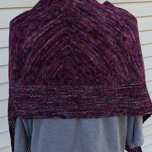 May include: A purple and black knitted shawl with a chevron pattern. The shawl is draped over a mannequin.