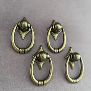 Fyra små lådhandtag i vintagemässing. Möbelknoppar i antikmässing i klassisk elegans.