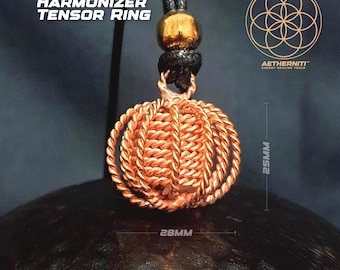 Könnte beinhalten: Ein Harmonizer Tensor Ring Anhänger aus Kupferdraht mit einem kugelförmigen, geflochtenen Design, aufgehängt an einer schwarzen Kordel mit einer goldfarbenen Perle. Der Anhänger misst 25mm in der Höhe und 28mm in der Breite. Text: Harmonizer Tensor Ring und Aetherniti.
