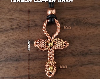 May include: A copper wire Ankh pendant featuring twisted wire construction, three small gold-toned beads, and a black cord. The text TENSOR COPPER ANKH is visible. Measurements indicate a height of 65mm and a width of 38mm, with labels 144 and 188.