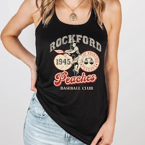 May include: Black tank top featuring the text "Rockford Peaches Baseball Club" in a vintage design. The graphic includes the year 1945 and a baseball player illustration. The top has a racerback style.