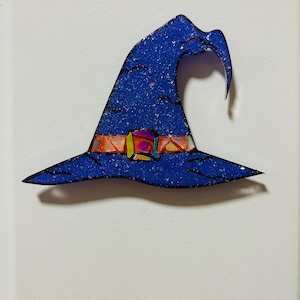 May include: A blue witch hat with a glittery texture and a black outline. The hat features a colorful belt with orange, yellow, and purple accents. The hat is a Halloween decoration.