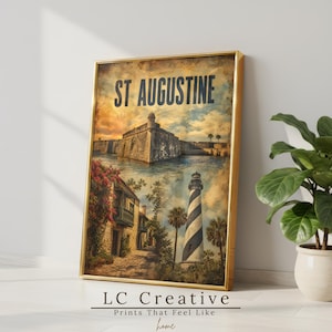 May include: A framed vertical wall art print featuring the text ST AUGUSTINE at the top. The image displays a stone fortress by the water, a historic building with red flowers, and a tall lighthouse with black and white diagonal stripes.
