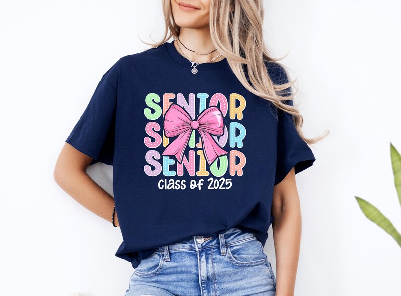 May include: Navy blue t-shirt with a colourful "Senior" graphic and a pink bow. The text "Class of 2025" is printed below the graphic.
