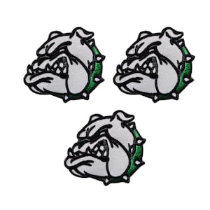 Puede incluir: Tres parches bordados con la cabeza de un bulldog. Los parches son blancos con contornos negros y un borde verde. El bulldog tiene una expresión feroz, con los dientes a la vista. Los detalles son precisos.