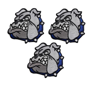 Puede incluir: Tres parches bordados con la cabeza de un bulldog con una expresión feroz. Los parches tienen detalles grises y negros, un borde azul y detalles blancos. El bulldog gruñe, con la lengua fuera.