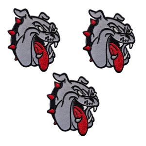 Puede incluir: Tres parches bordados con la cabeza de un bulldog gris con lengua roja y púas rojas. El bulldog tiene una expresión feroz con la boca abierta, los dientes descubiertos y la lengua fuera. Sobre un fondo blanco.