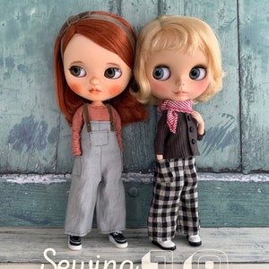 May include: Two dolls wearing different outfits. The doll on the left is wearing a red and white striped long-sleeved shirt, grey overalls, and black shoes. The doll on the right is wearing a brown sweater, a red and white checked scarf, black and white checked trousers, and white shoes. The dolls are standing on a wooden surface. The text "Sewing pattern 19" is written in white on a white background.