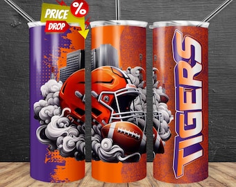 May include: Three stainless steel tumblers with football designs. One is purple with an orange cityscape and football helmet. The second is orange with a helmet and football. The third is orange with the word "TIGERS" in purple.