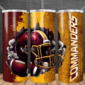 Könnte beinhalten: Ein Set aus drei Edelstahl-Bechern mit einem Design, das einen Footballhelm, einen Football und das Wort "COMMANDERS" in einer stilisierten Schrift zeigt. Die Becher sind mit einem gelben und braunen Muster verziert.