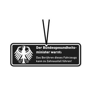 Könnte beinhalten: Ein schwarz-weißes rechteckiges Schild mit dem deutschen Bundesadler-Emblem und Text. Auf dem Schild steht "Der Bundesgesundheitsminister warnt: Das Berühren dieses Fahrzeugs kann zu Zahnausfall führen!"