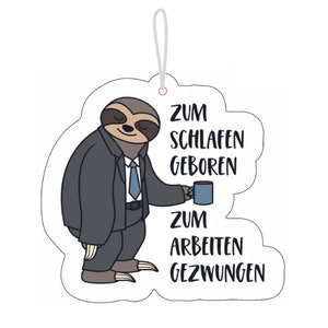 Pode incluir: Um bicho-preguiça de desenho animado vestindo um terno e gravata segura uma xícara de café. O texto diz "Zum Schlafen Geboren Zum Arbeiten Gezwungen".