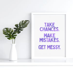 May include: A white framed print with a purple watercolour design. The text on the print reads "Take Chances. Make Mistakes. Get Messy."