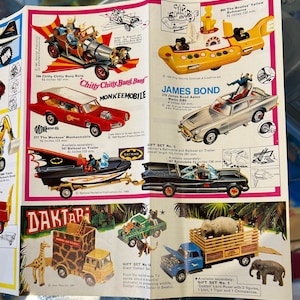 May include: A collection of vintage toy cars, including the Chitty Chitty Bang Bang car, the Monkees' Monkeemobile, James Bond's Aston Martin DBS, and the Beatles' Yellow Submarine. The toys are all in various shades of red, blue, yellow, and black. The image also includes a toy truck with a giraffe and an elephant, and a toy truck with a tiger and a chimpanzee.