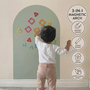 May include: A sage green arch-shaped wall board featuring magnetic geometric shapes in red, yellow, and blue. The board includes text reading 3-IN-1 MAGNETIC ARCH, MAGNET BOARD, CHALK BOARD, WALL DECOR, and WIPES CLEAN EASILY with corresponding icons.