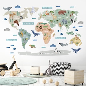 May include: A colorful world map wall decal with animal illustrations and continent names. The map features a light blue, green, and brown color scheme with white outlines. The continents are labeled with the names of the continents and oceans. The animals are illustrated in a cartoon style and include a giraffe, a lion, a penguin, a koala, a narwhal, a turtle, a crocodile, and a toucan.