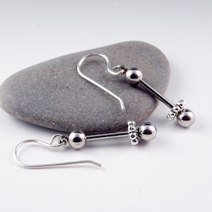 May include: A pair of silver earrings with a small ball and a beaded ring on each earring.