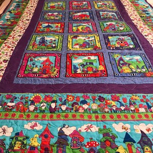 May include: A colorful quilt with a purple background and a pattern of framed images of gnomes and houses. The quilt has a border of green, blue, and white with a pattern of gnomes and flowers.