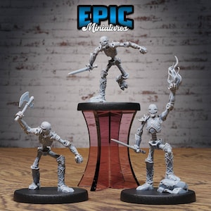 Könnte beinhalten: Drei graue Plastik-Miniaturfiguren von Skeletten mit verschiedenen Waffen und Posen. Die Figuren stehen auf schwarzen Sockeln und werden auf einem rosa und schwarzen Podest ausgestellt. Die Figuren sind mit "EPIC Miniatures" beschriftet.