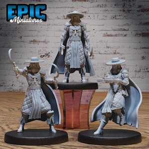 Puede incluir: Tres figuras en miniatura grises de un personaje con sombrero y capa, empuñando armas. Las figuras están sobre bases negras, una de ellas de pie sobre una plataforma transparente teñida de rojo. El texto "EPIC Miniatures" está en la esquina superior izquierda.
