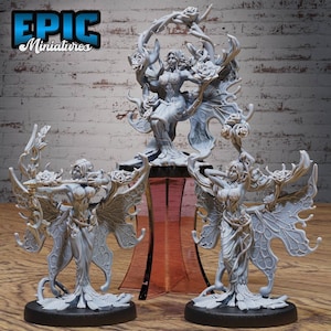 May include: Three miniature figurines of fairies with wings made of leaves and flowers. The fairies are painted in a light grey colour and are standing on bases with a black rim. The middle fairy is standing on a pink pedestal.