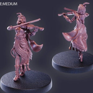 以下が含まれることがあります： バイオリンを演奏している女性のミニチュアフィギュア。フィギュアは、複雑なディテールとケープが付いた長い流れるようなドレスを着ています。フィギュアは薄い茶色に塗られており、丸い台座の上に立っています。