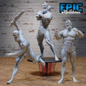 Puede incluir: Tres figuras en miniatura pintadas de gris de figuras musculosas con cuernos. Las figuras están representadas en diferentes posturas de acción. Las figuras están de pie sobre una base circular negra con un diseño rojo y dorado.