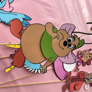 May include: A set of five cartoon character cutouts on sticks. The characters include a blue bird, a brown mouse with a green shirt, a pink mouse with a white dress, a brown mouse with a red dress, and a brown mouse with a pink dress.