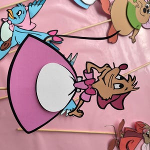 May include: A set of five paper cutouts of characters from the Disney movie Cinderella. The characters include Cinderella, Gus, Jaq, the mice, and Lucifer, the cat. The cutouts are on sticks and are ready to be used as party decorations.