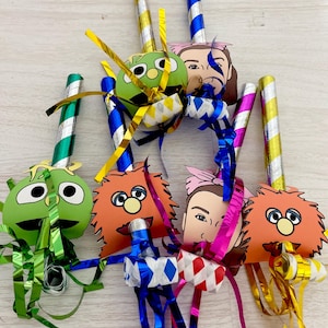 Puede incluir: Una colección de matasuegras coloridos con caras de personajes. Los matasuegras presentan caras verdes, naranjas y rosas, con tubos a rayas doradas, plateadas y azules. Cada matasuegras tiene serpentinas metálicas de varios colores.